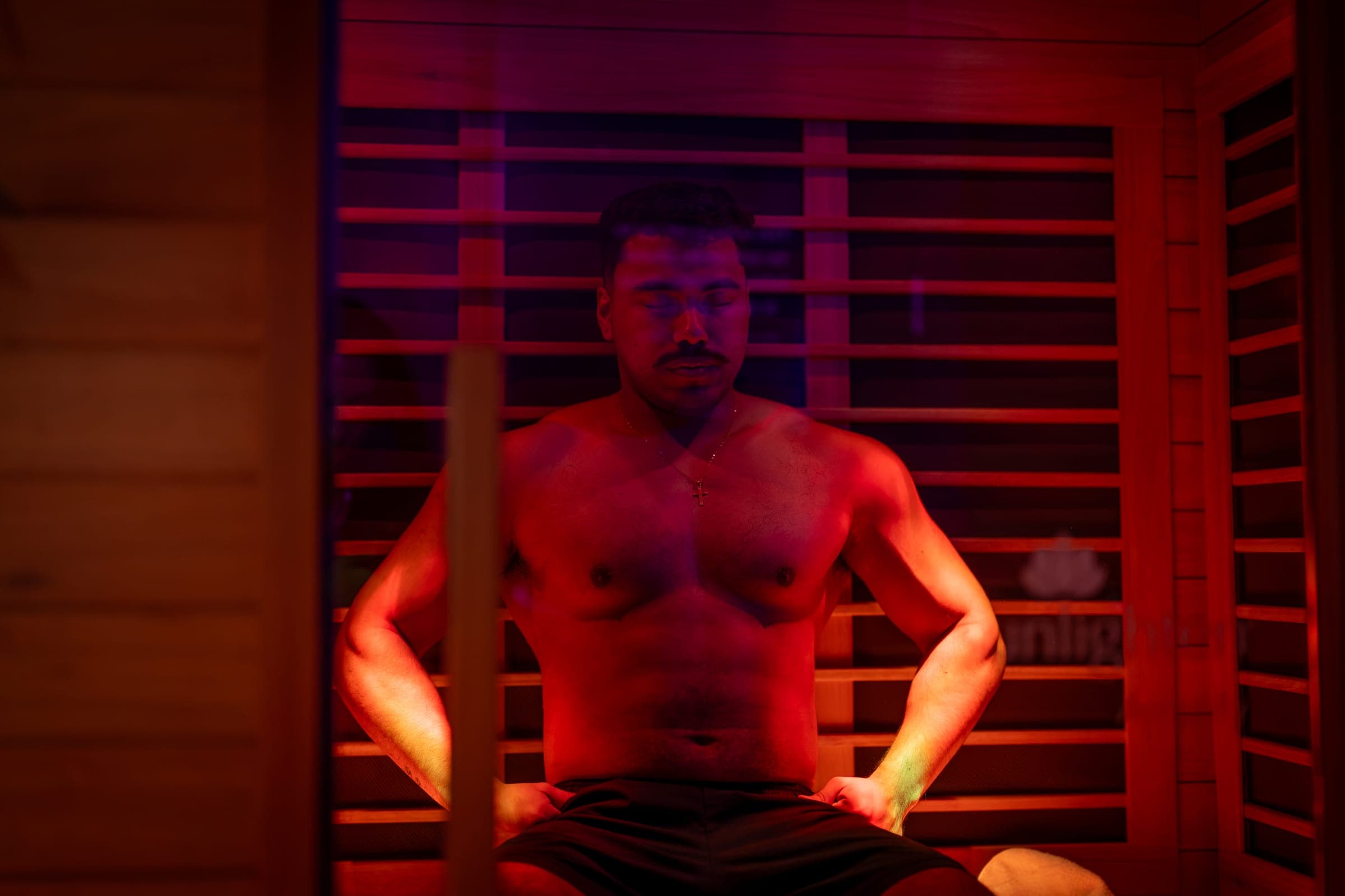 Infrared sauna after a workout: a guest sits in the red-lit sauna at Conscious Body Recovery