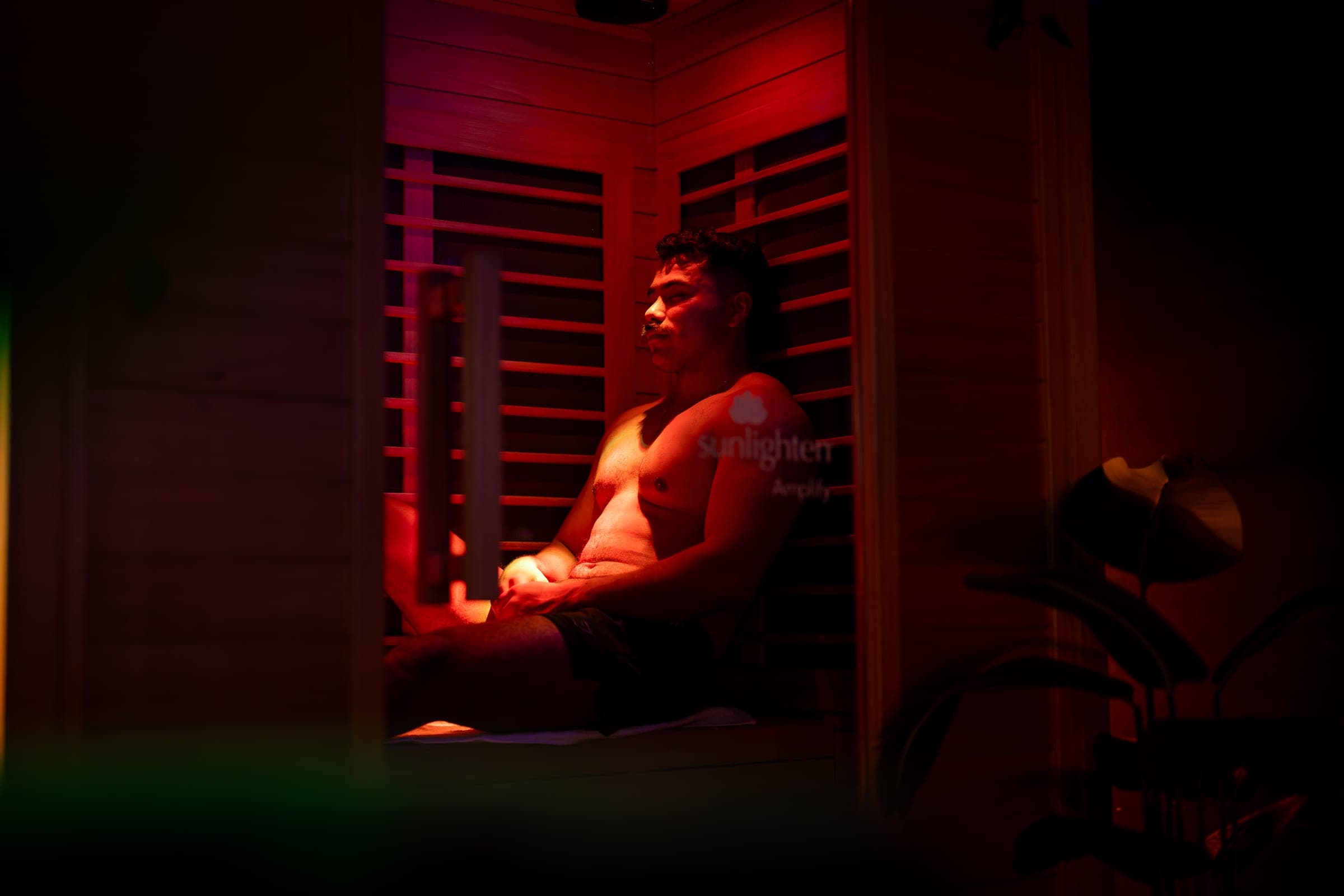 Inside the infrared sauna at CBR: a guest sits back on the wooden bench in warm red light